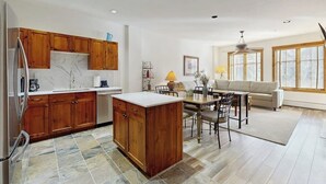 Eine moderne Küche mit Holzschränken, einer Marmorarbeitsplatte und einem Essbereich mit Tisch und Stühlen.