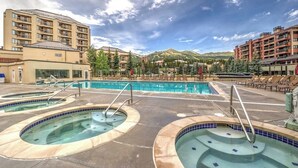 Un hôtel doté de plusieurs piscines, situé au pied d’une chaîne de montagnes et offrant une vue sur un ciel dégagé.