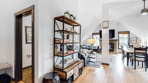A spacious living area with a high ceiling, a wooden floor, a bookshelf, a fireplace, and a dining area. - Penthouse with balcony, pool, hot tubs & gym - walk to lifts & Main Street (Breckenridge)