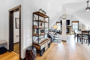 A spacious living area with a high ceiling, a wooden floor, a bookshelf, a fireplace, and a dining area. - Penthouse with balcony, pool, hot tubs & gym - walk to lifts & Main Street (Breckenridge)
