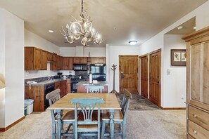 Una cocina con armarios de madera, una mesa de comedor con sillas y una araña.