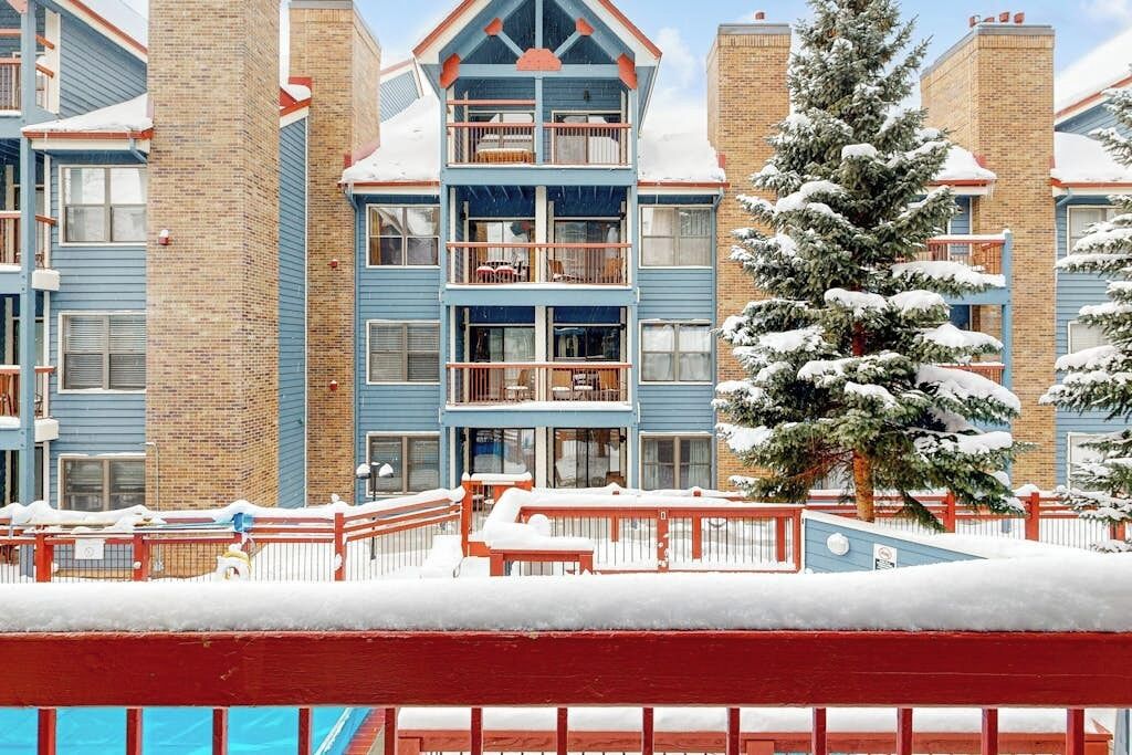 Ein mehrstöckiges Hotel mit Balkonen, Backsteinschornsteinen und einer verschneiten Landschaft.