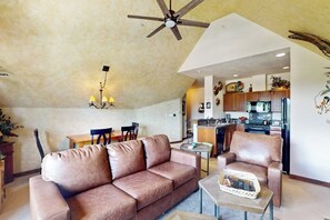 Un salon comprenant un canapé, un fauteuil, une table à manger et un ventilateur de plafond.