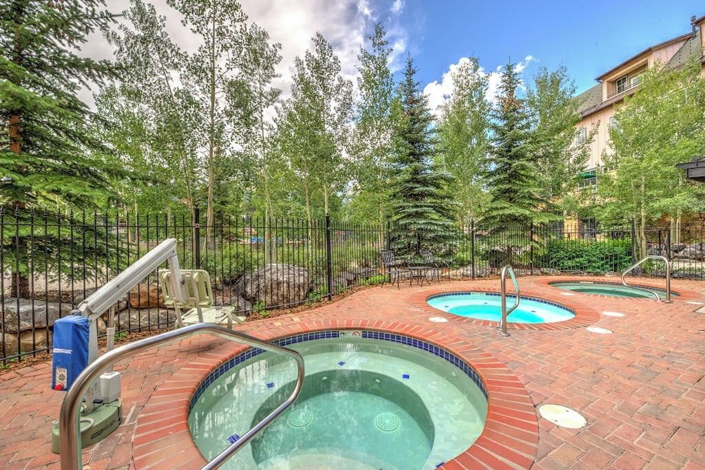 Ein Whirlpoolbereich mit Pflasterterrasse, umgeben von einem Zaun und Bäumen.