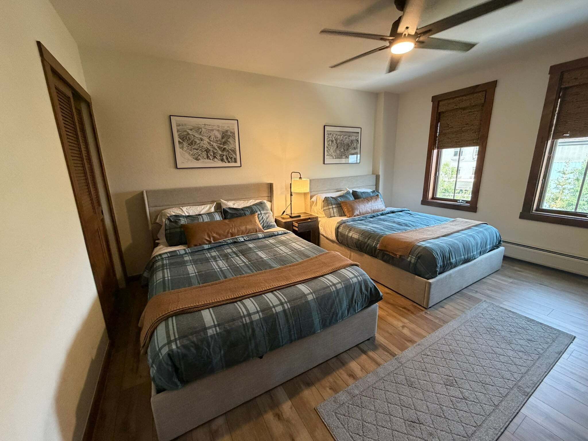 Quarto com duas camas, ventilador de teto e obras de arte nas paredes.