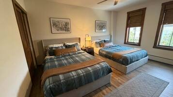 Quarto com duas camas, ventilador de teto e obras de arte nas paredes.
