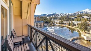 Een balkon met uitzicht op een rivier, bergen en gebouwen.