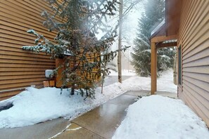 A snow-covered pathway leading to a building with wooden siding and a covered porch. - Modern Keystone condo w/ a gas fireplace & shared hot tub (Keystone)