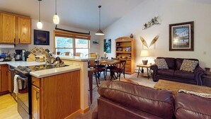 Una cocina con armarios de madera, un comedor con sillas, un sofá y una lámpara.