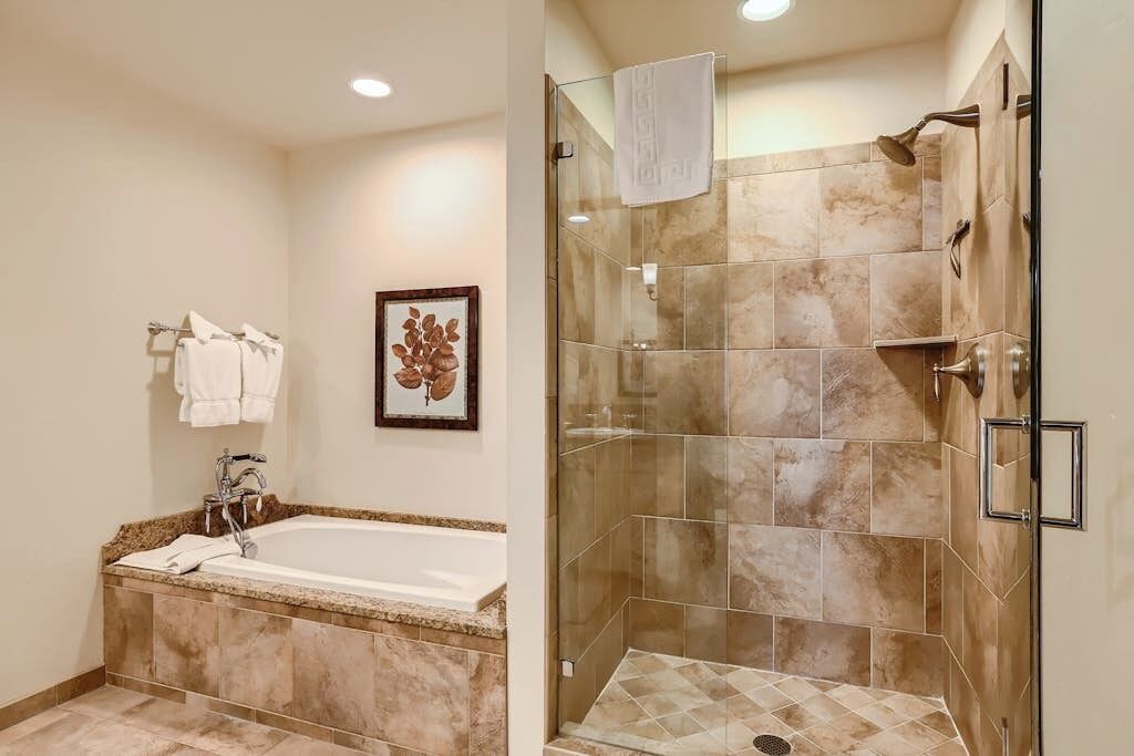 A bathroom with a bathtub, a shower, and a framed picture on the wall.
