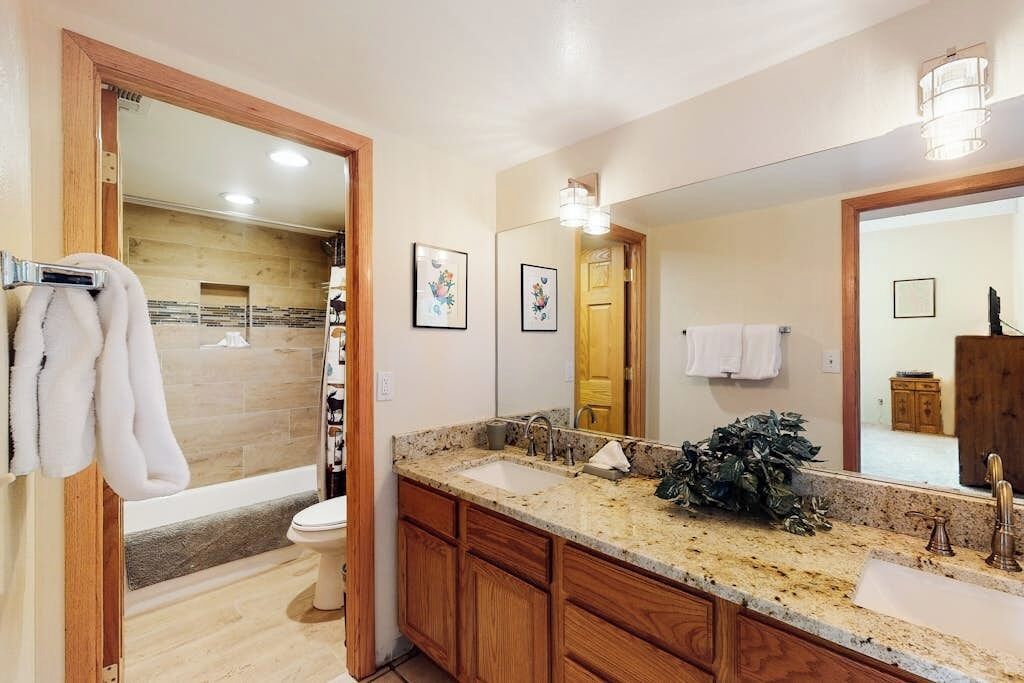 A bathroom with wooden cabinets, a large mirror, and a shower area.