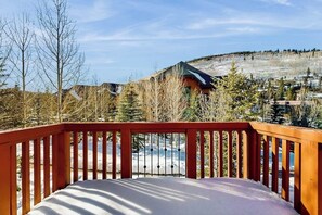 A snow-covered deck with a view of a mountain and buildings. - Cozy townhome with fully stocked kitchen, fast wifi & easy ski access (Copper Mountain)