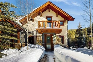 A two-story lodge with a stone facade, a wooden balcony, and a snow-covered entrance. - Cozy townhome with fully stocked kitchen, fast wifi & easy ski access (Copper Mountain)