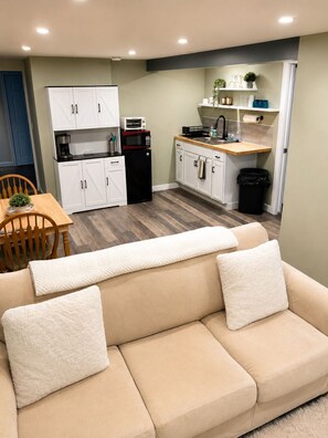A kitchenette with white cabinets, a microwave, and a coffee maker.