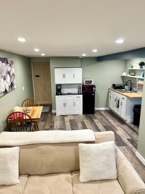 A compact living space with a kitchenette, a dining area, and a sofa with cushions.
