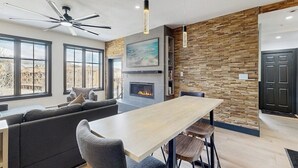 A modern kitchen with a fireplace, a dining area, and a seating area with a sofa and chairs. - Charming, walk-to-lifts condo with hot tubs, pool, gym & gas fireplace (Breckenridge)
