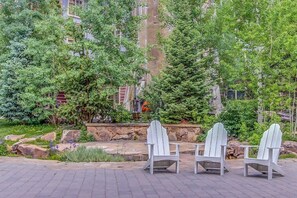 Eine Terrasse mit Adirondack-Stühlen, einer Steinmauer und vielfältigem Grün.
