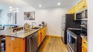 Eine moderne Küche mit Holdekor, einer Arbeitsplatte aus Granit, Edelstahlgeräten und einem Essbereich mit Sofa und Tisch.