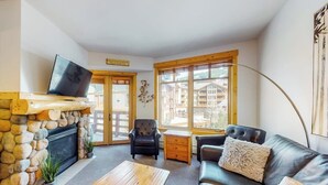 Ein Wohnzimmer mit Kamin aus Stein, einem Fernseher, einer Couch und einem Couchtisch.