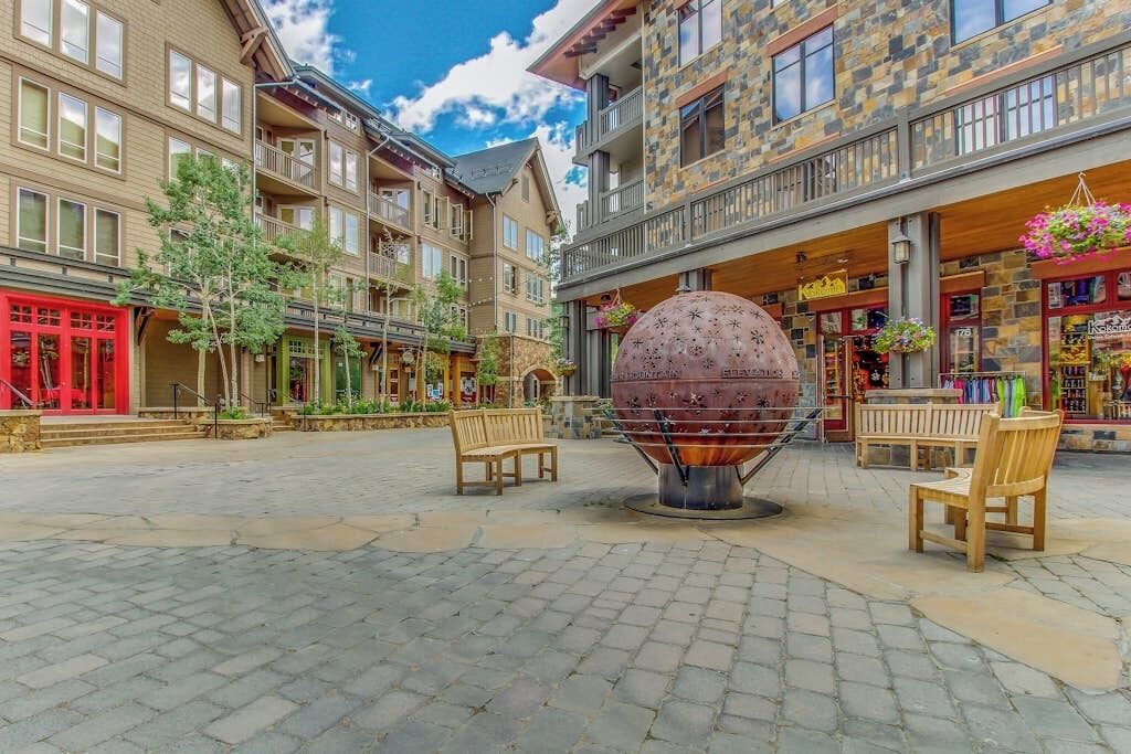 A building with multiple floors, balconies, and a central courtyard with a spherical sculpture.