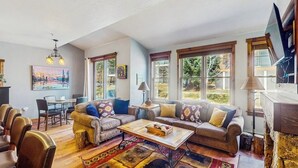 Ein geräumiges Wohnzimmer mit einer Sofagarnitur, einem Couchtisch und einem Essbereich mit Stühlen.