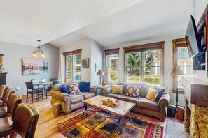 Ein geräumiges Wohnzimmer mit einer Sofagarnitur, einem Couchtisch und einem Essbereich mit Stühlen.