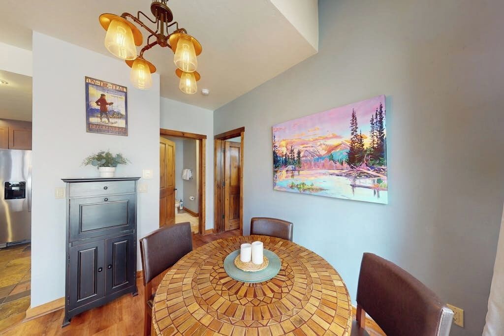 Un coin repas avec une table à motifs en mosaïque, des meubles en bois, un tableau et un lustre.