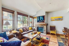 Ein Wohnzimmer mit Kamin, einer Couch, einem Couchtisch und einem Fernseher.