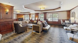 Eine großzügige Hotelhalle mit mehreren Sitzbereichen, einem Kamin und großen Fenstern.