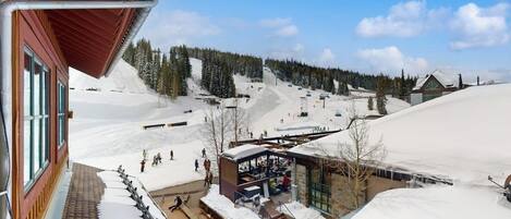 A ski resort with a building, a covered outdoor area, and a snowy landscape.