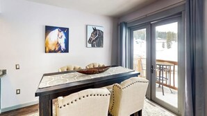 Uma área de refeições com mesa, cadeiras e duas obras de arte com tema de cavalos.