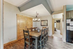 A dining area with a wooden table and chairs, a chandelier, and wooden cabinets. - Family-Friendly Townhouses with WiFi, Wood Fireplaces, and Private Washer/Dryers (Breckenridge)