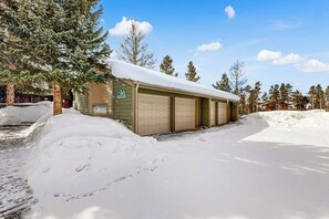 A single-story building with a garage, surrounded by snow and trees. - Cozy condo w/ a private hot tub & Fraser Valley views (Fraser)