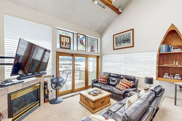 A living room with a fireplace, a sofa, a coffee table, and a bookshelf. - Cozy condo w/ a private hot tub & Fraser Valley views (Fraser)
