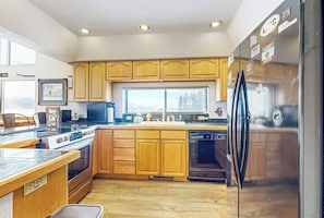 A kitchen with wooden cabinets, a stainless steel refrigerator, a stove, and a dishwasher. - Cozy condo w/ a private hot tub & Fraser Valley views (Fraser)