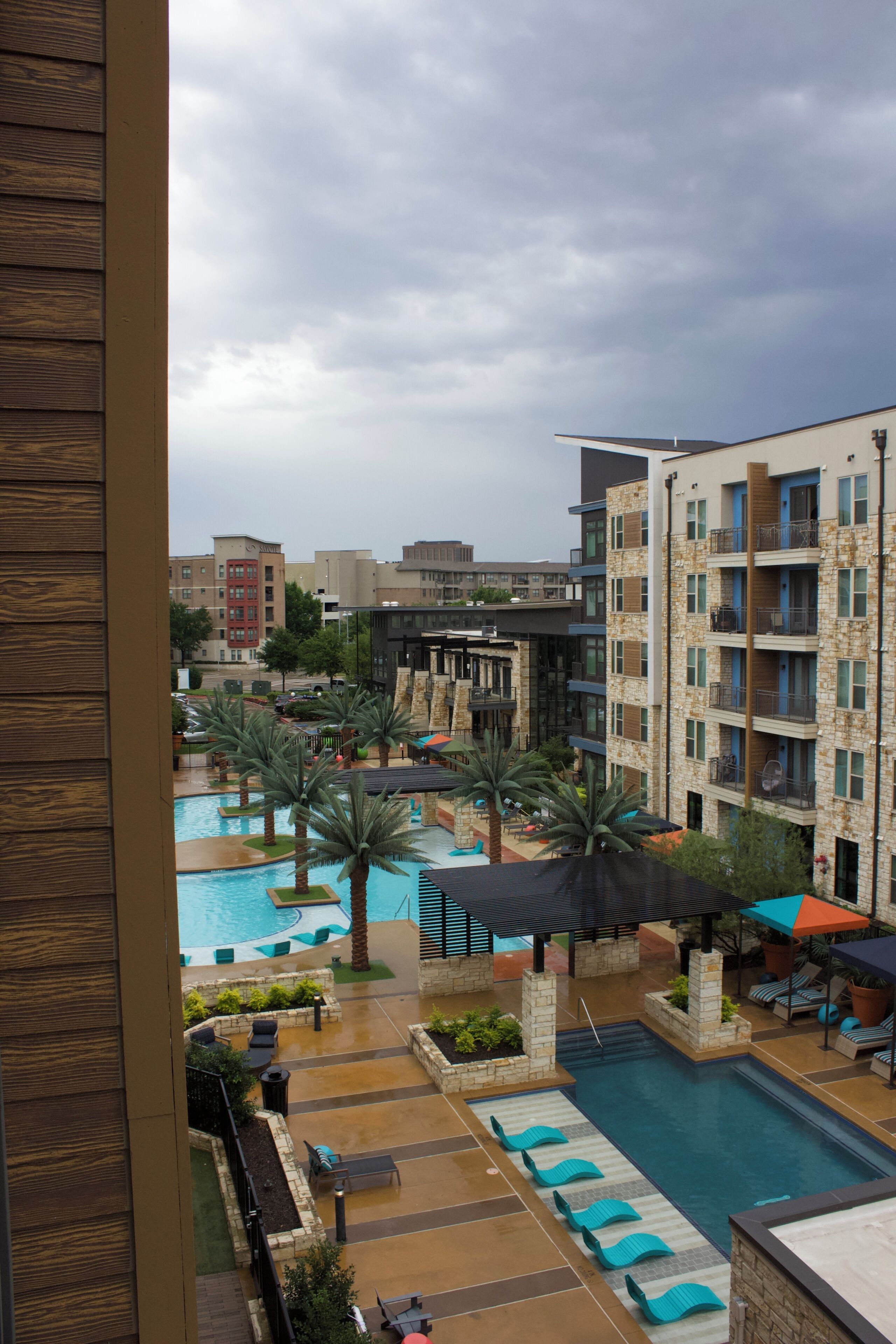 A hotel with a swimming pool, lounge chairs, and a view of surrounding buildings.