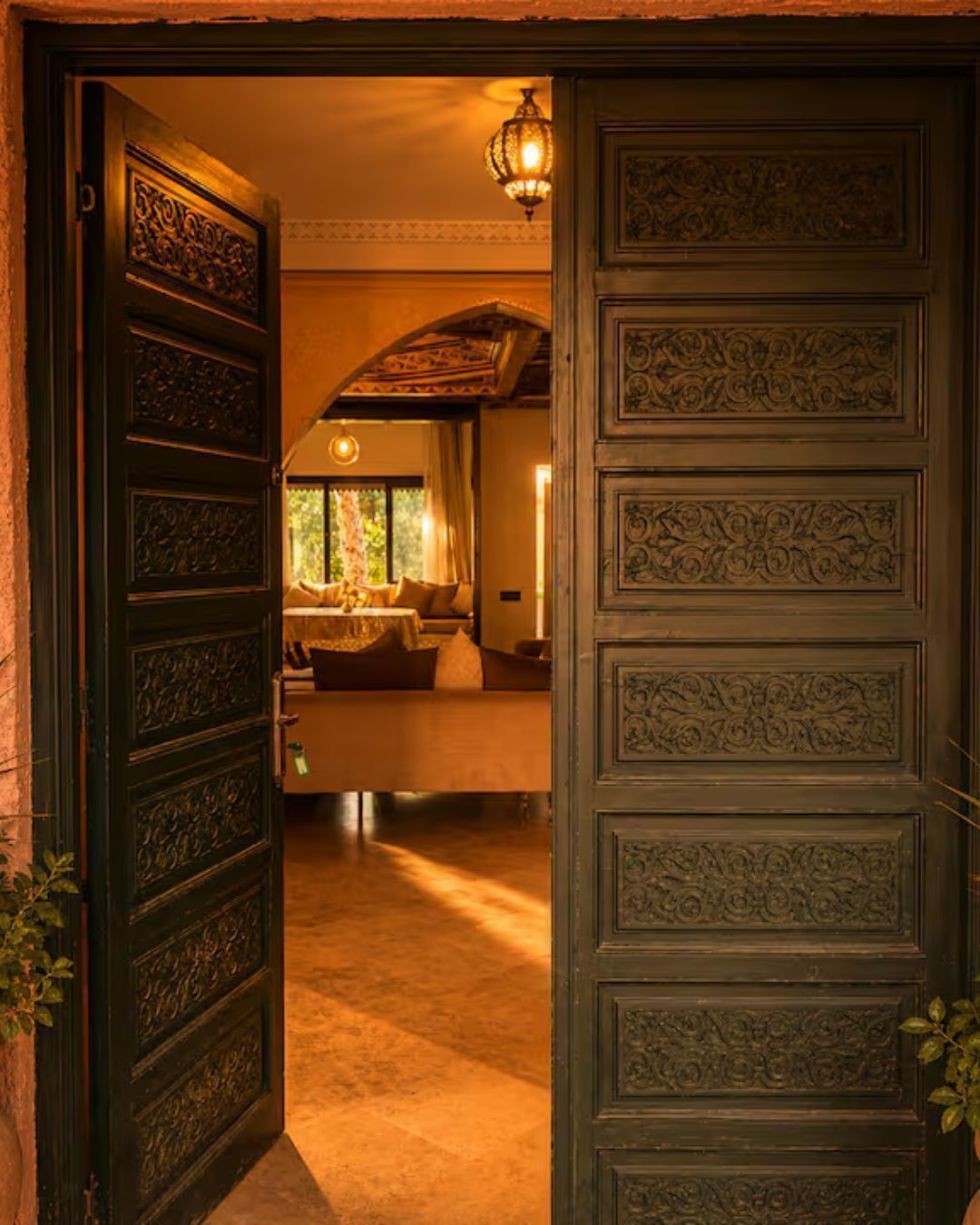 A doorway leading to a room with a bed, a window, and a hanging light fixture.