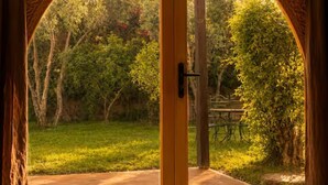 Ein Bogenportal führt zu einem Außenbereich mit Terrasse und Grünflächen.