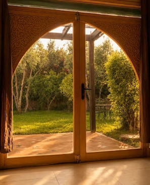 Un vano con diseño de arco que da a un espacio exterior con patio y vegetación.