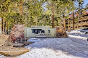 Opastekyltti, jossa lukee ”Tyra 1 Summit”, ja taustalla näkyy kivirakennelma ja puita.