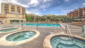 Um hotel com várias piscinas, paisagem montanhosa e céu limpo.