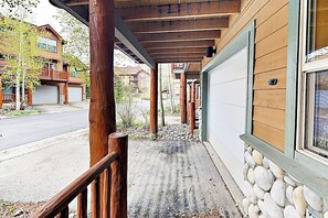Eine überdachte Veranda mit Holzgeländern, einer Steinmauer und einer Garagentür.