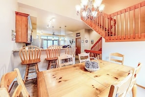 Ein Essbereich mit Holztisch und Stühlen, einer Chandelier und einer Treppe.