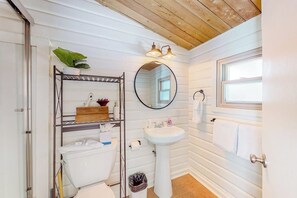 Ein Badezimmer mit Waschbecken, Spiegel, Holzboden und Fenster.