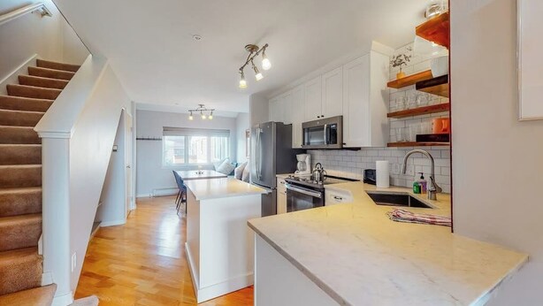 Una cucina moderna con mobili bianchi, un'isola centrale e un forno integrato.