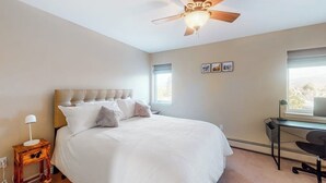 Una camera da letto con un letto, una scrivania, una ventola a soffitto e una finestra.
