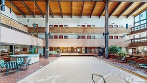 A multi-level indoor swimming pool with a covered area, seating, and a bar area. - Charming Condo with Indoor Pool and Hot Tub - On Bus Line Half-Mile to Slopes (Crested Butte)