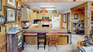 A wooden cabin interior with a kitchen, dining area, and a small bar. - Serene mountainside cabin, with washer/dryer - near skiing (Almont)