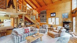 A spacious log cabin interior with a staircase, multiple seating areas, and a kitchen. - Serene mountainside cabin, with washer/dryer - near skiing (Almont)