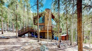 A cabin in a forest with a wooden deck and a stone chimney. - Serene mountainside cabin, with washer/dryer - near skiing (Almont)
